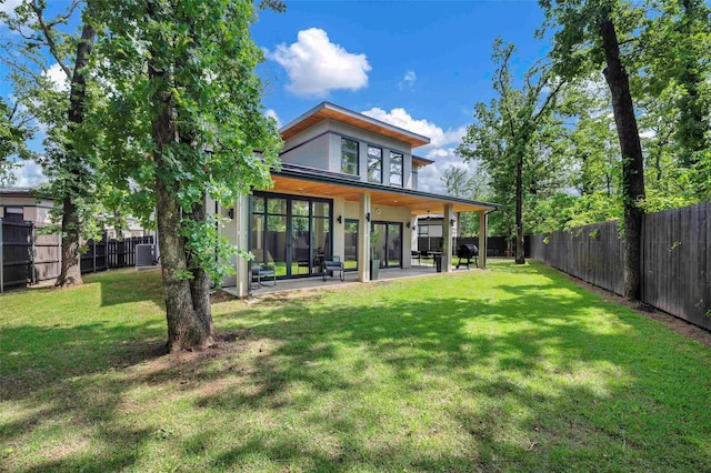 back of property featuring a fenced backyard, a patio area, and a yard