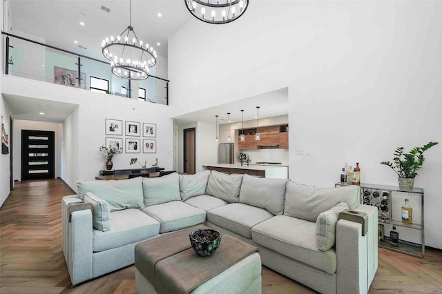 living room featuring a towering ceiling, visible vents, and a chandelier