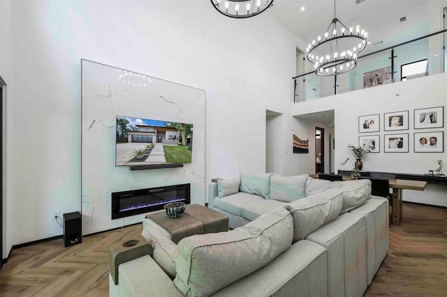 living room with an inviting chandelier, a glass covered fireplace, and a high ceiling
