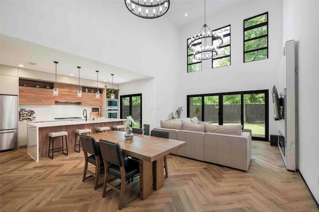 dining area featuring recessed lighting, a notable chandelier, plenty of natural light, and a towering ceiling
