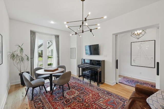 dining area with light wood-style floors, recessed lighting, baseboards, and a notable chandelier