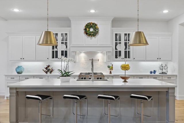 kitchen with light countertops, white cabinets, a breakfast bar, and backsplash