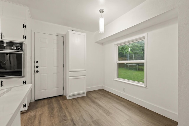 unfurnished dining area with baseboards and light wood-style flooring