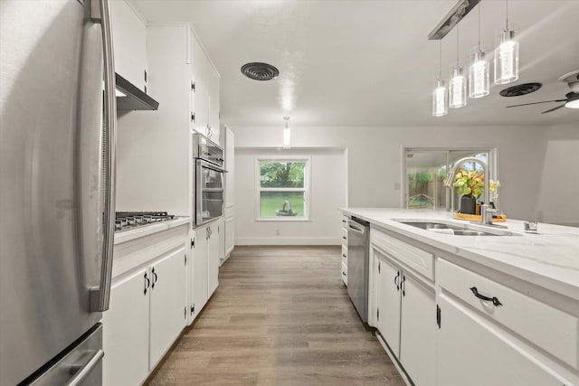 kitchen featuring a sink, appliances with stainless steel finishes, light wood finished floors, and white cabinetry