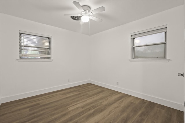 empty room with baseboards, dark wood finished floors, and ceiling fan