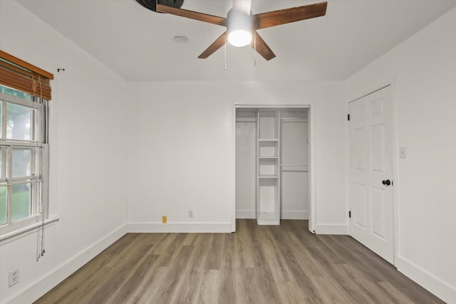 unfurnished bedroom with baseboards, multiple windows, and wood finished floors