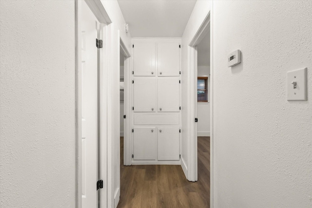 corridor featuring a textured wall and dark wood-style floors