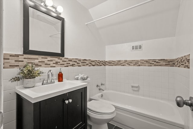 full bath with visible vents, vanity, toilet, tile walls, and a bathtub