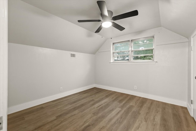 additional living space featuring visible vents, lofted ceiling, wood finished floors, baseboards, and a ceiling fan