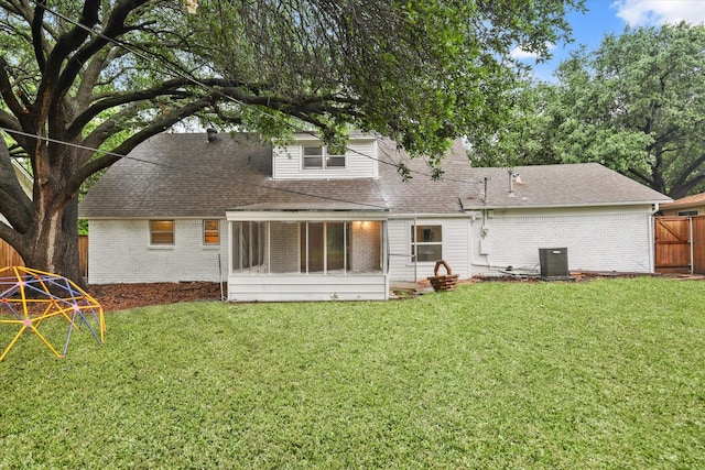 rear view of house with a fenced backyard, a yard, roof with shingles, and brick siding