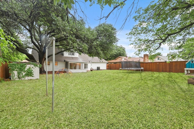 view of yard featuring a storage unit, a fenced backyard, a trampoline, and an outdoor structure