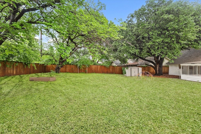 view of yard with an outdoor structure, a fenced backyard, and a storage unit