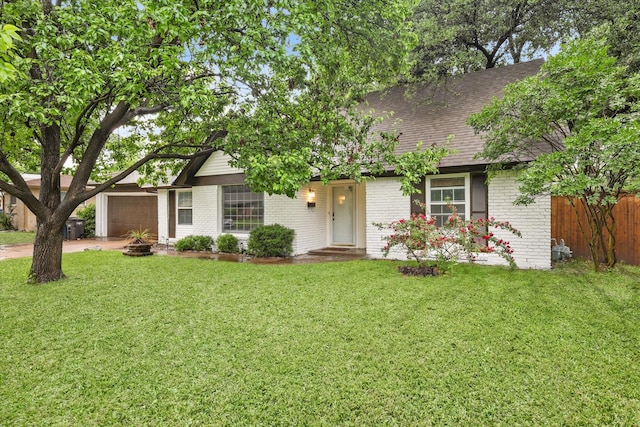 view of front facade with a front lawn, fence, roof with shingles, brick siding, and an attached garage
