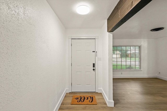 entryway featuring baseboards, a textured wall, and wood finished floors