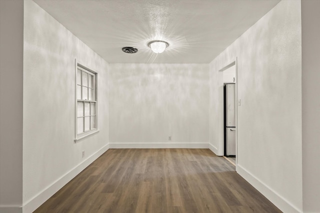 spare room with baseboards and dark wood-style flooring