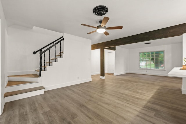 unfurnished living room with baseboards, a ceiling fan, stairs, and wood finished floors