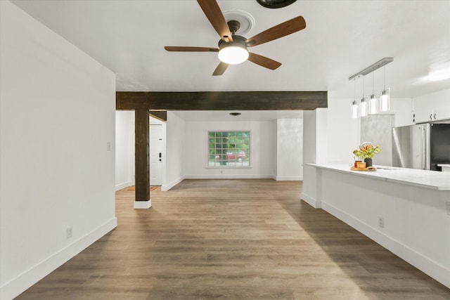 unfurnished living room with baseboards, ceiling fan, wood finished floors, and beamed ceiling