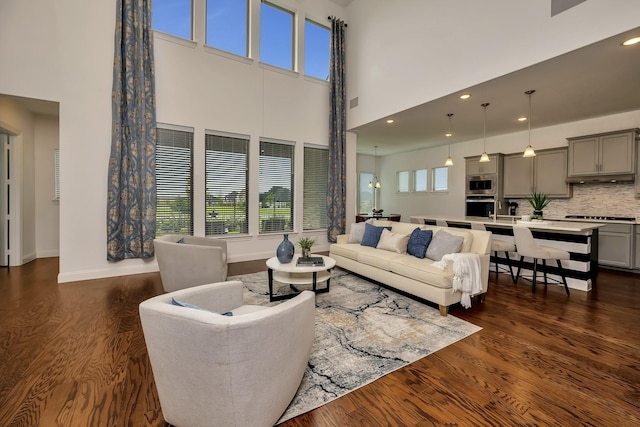 living room featuring recessed lighting, baseboards, a high ceiling, and dark wood-style flooring