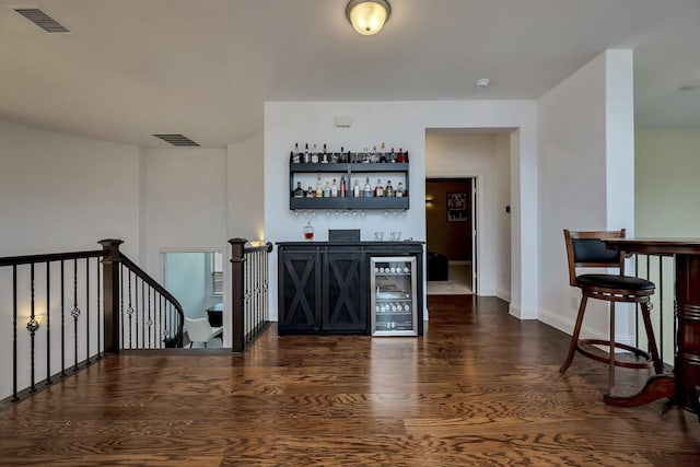 bar with baseboards, visible vents, a dry bar, and dark wood finished floors