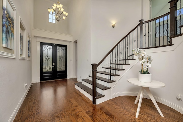 foyer entrance featuring an inviting chandelier, stairs, wood finished floors, a high ceiling, and french doors