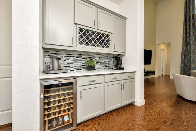 bar featuring beverage cooler, dark wood finished floors, tasteful backsplash, and a bar