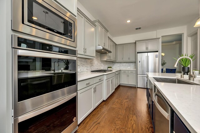 2203 Miranda Ln, Rockwall, TX 75087 - kitchen featuring stainless steel appliances, dark wood-style floors, gray cabinets, a sink, and decorative backsplash