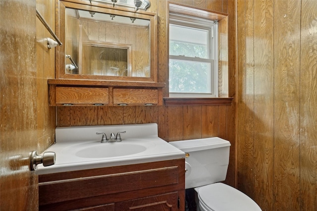 half bathroom with wooden walls, vanity, and toilet