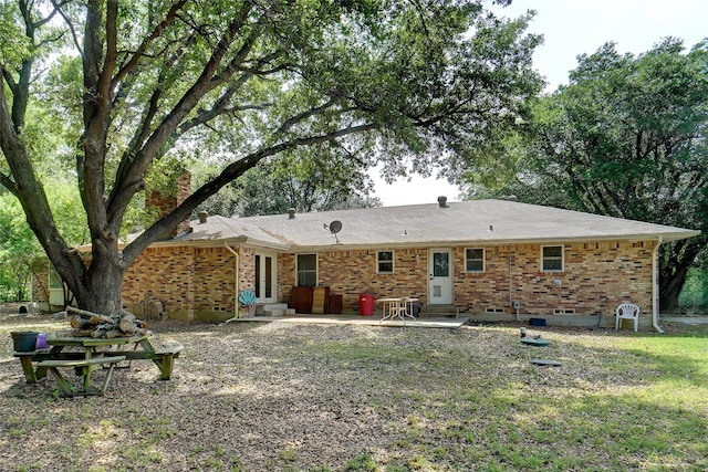 back of house featuring brick siding, a chimney, a patio area, and entry steps