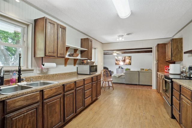 kitchen featuring open shelves, a sink, light wood-style floors, a textured ceiling, and stainless steel appliances