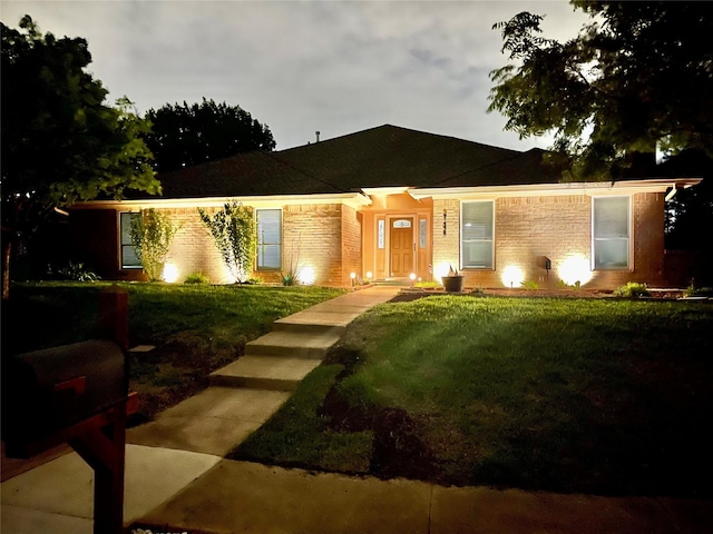 single story home with brick siding and a front yard