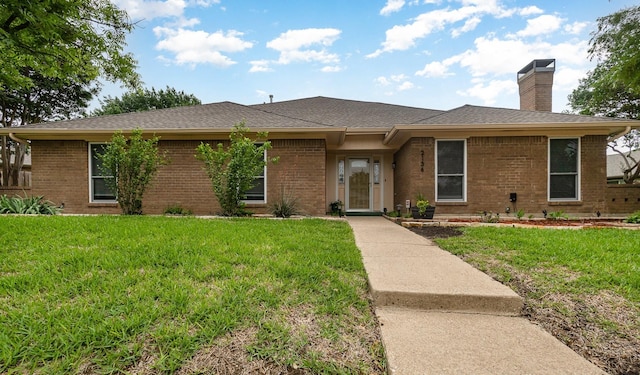 ranch-style house with brick siding, a chimney, roof with shingles, and a front lawn