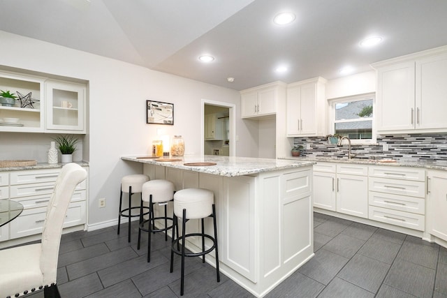 kitchen with decorative backsplash, a breakfast bar, a peninsula, and white cabinetry