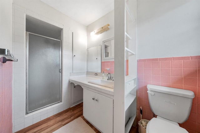 full bathroom with vanity, toilet, tile walls, wood finished floors, and a stall shower