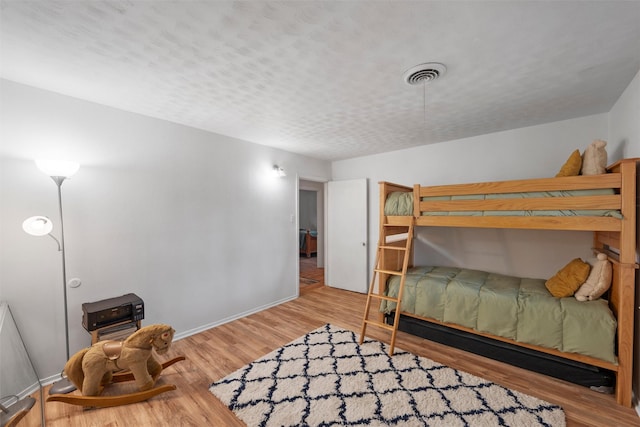 bedroom with baseboards, visible vents, and wood finished floors