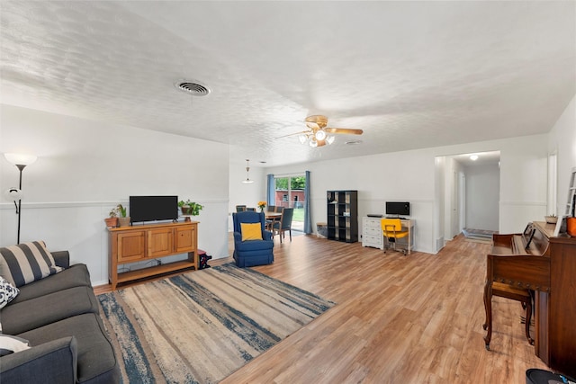 living room with visible vents, light wood-style floors, ceiling fan, and baseboards