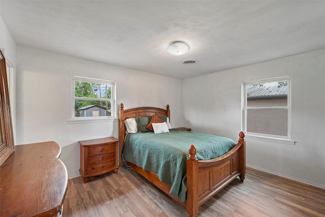 bedroom with baseboards, wood finished floors, and visible vents