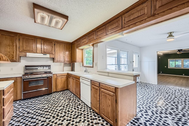 kitchen featuring dishwasher, a sink, a peninsula, under cabinet range hood, and gas range oven
