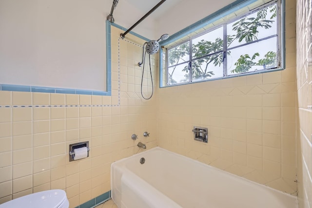 full bathroom with shower / bath combination, toilet, and tile walls