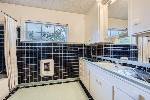 bathroom featuring tile patterned flooring, a textured ceiling, vanity, and tile walls