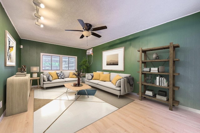 living room with baseboards, a textured ceiling, ceiling fan, and wood finished floors