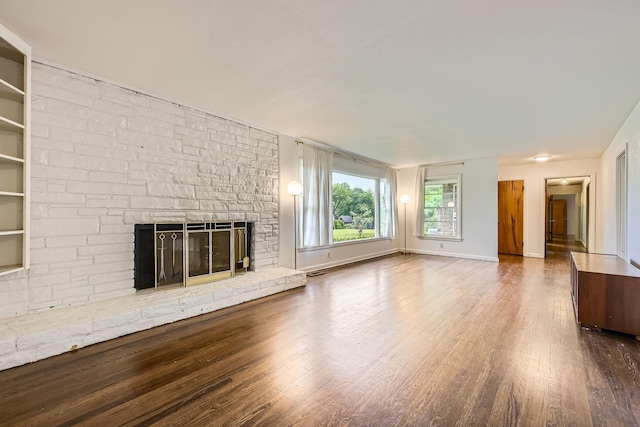 unfurnished living room with a stone fireplace, baseboards, wood finished floors, and visible vents