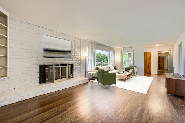 living area with baseboards, a large fireplace, and wood finished floors