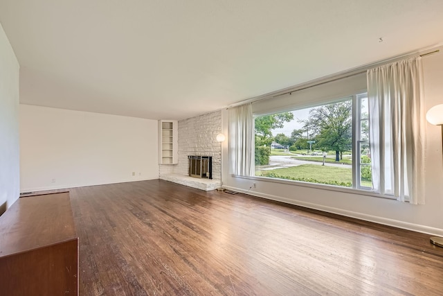 unfurnished living room featuring built in features, wood finished floors, and a healthy amount of sunlight