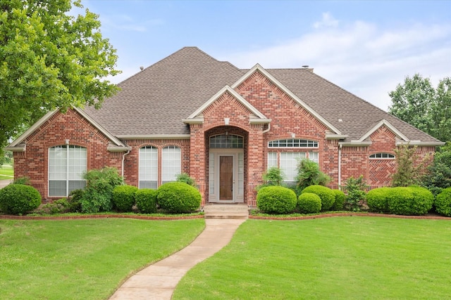 single story home with brick siding, a front yard, and roof with shingles