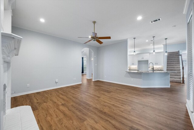 unfurnished living room featuring a sink, recessed lighting, arched walkways, a ceiling fan, and dark wood finished floors