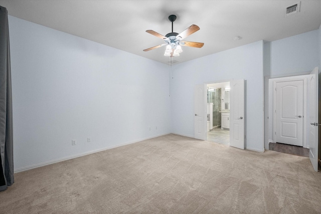 unfurnished bedroom featuring a ceiling fan, visible vents, baseboards, connected bathroom, and light carpet