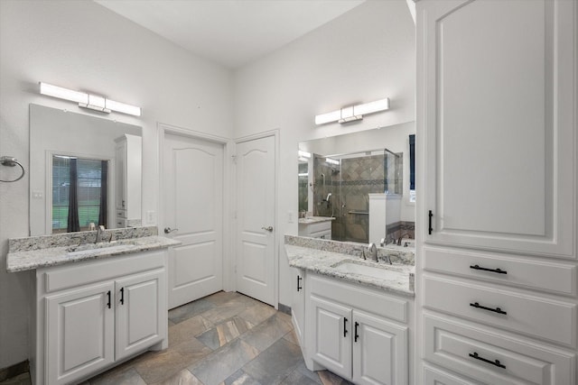 bathroom with a sink, stone finish flooring, a stall shower, and two vanities