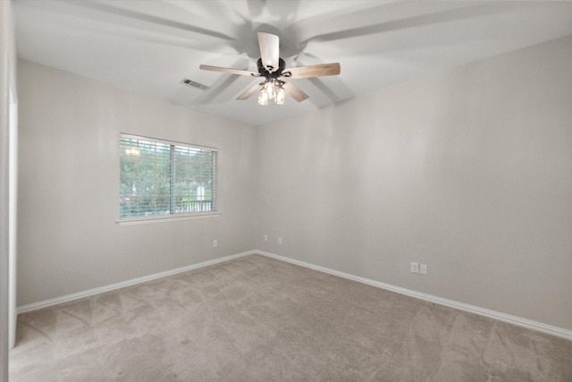 carpeted spare room featuring ceiling fan, visible vents, and baseboards