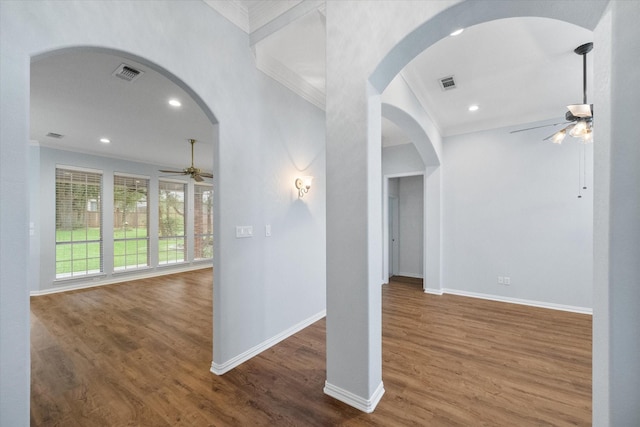 interior space featuring crown molding, baseboards, visible vents, and wood finished floors