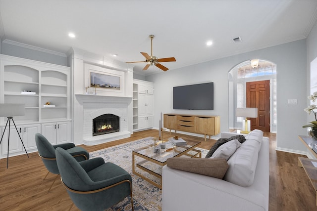 living area featuring crown molding, a ceiling fan, baseboards, wood finished floors, and visible vents